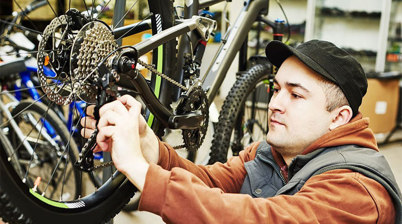 A mechanic is tightening a bike chain with a derailleur